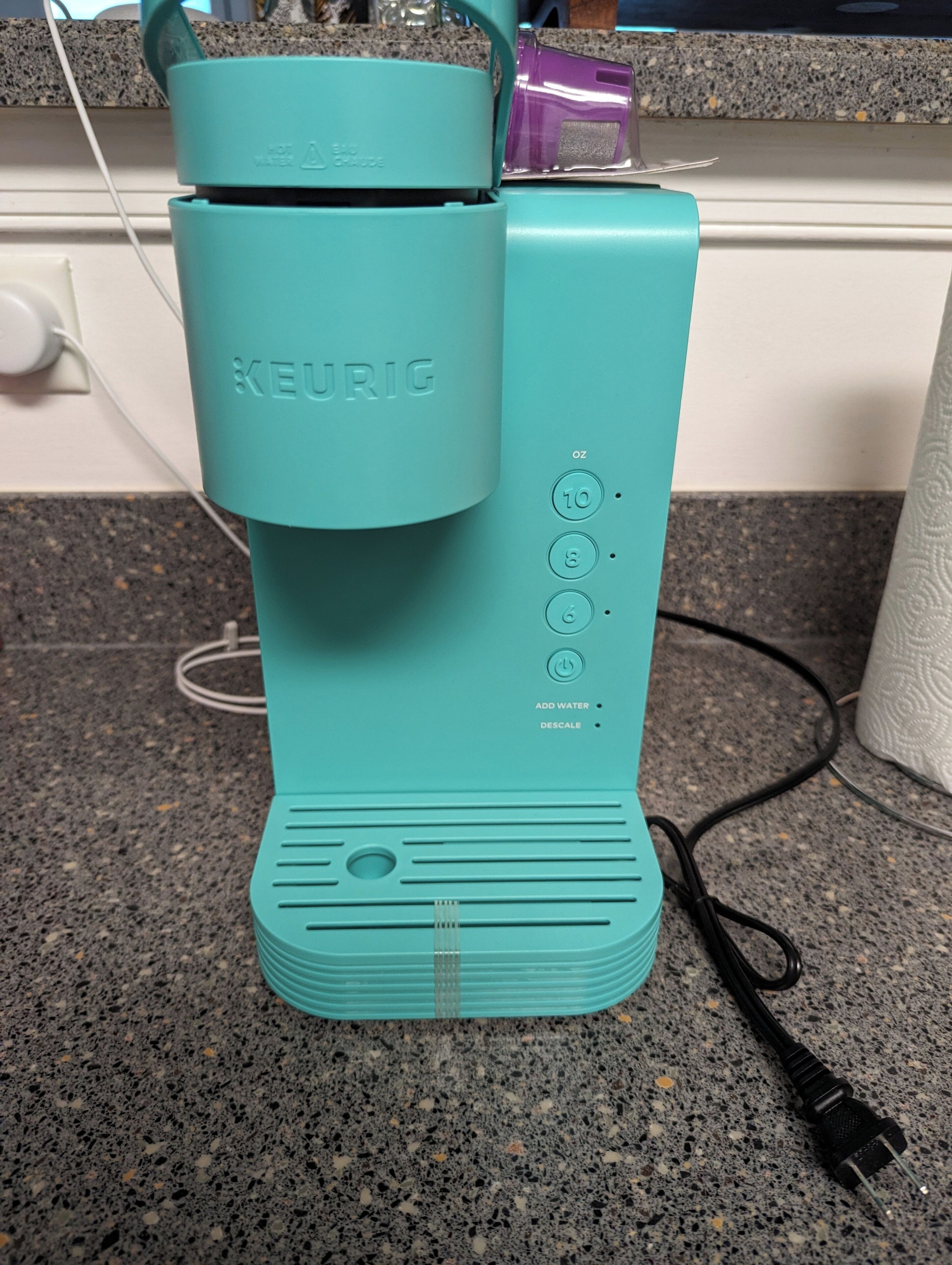 Turkoosinsininen Keurig-kahvinkeitin, jossa on virtajohto, ja se on sijoitettu graniittitasolle.