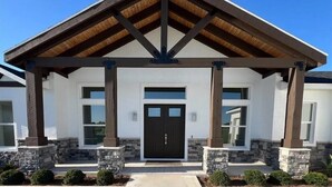 A building with a covered entrance, stone pillars, and a symmetrical facade.