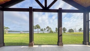 A spacious room with a large window overlooking a grassy area and a body of water.