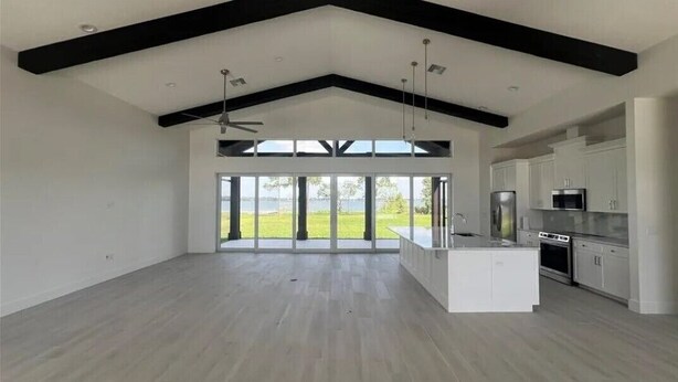 A spacious kitchen with a large island, modern appliances, and a view of a green landscape through large windows.