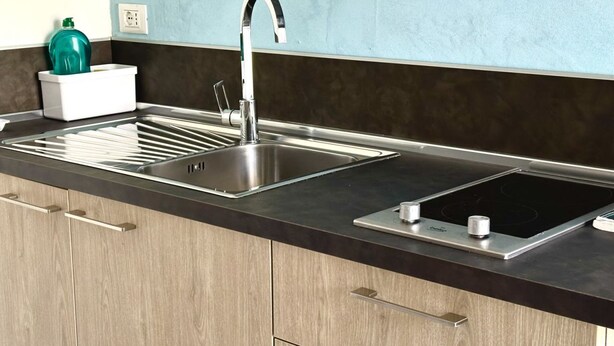 Una cocina con dos fregaderos de acero inoxidable, una encimera negra y armarios de madera.