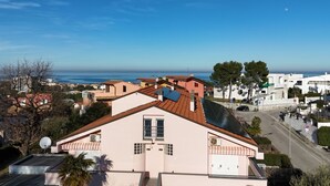 Zona residencial costera con casas, cielo despejado y vista al mar.