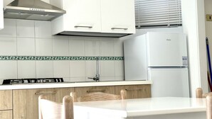 Eine Küche mit weißen Schränken, einem Gasherd, einer Spüle und einem weißen Kühlschrank.