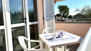 Ein Balkon mit Tisch, Stühlen und einem Fenster mit Rollläden.