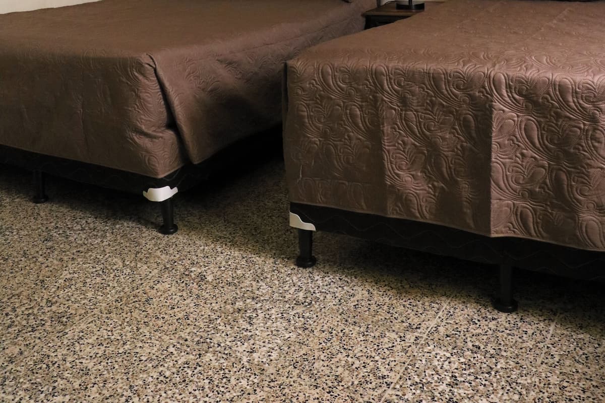 Ein Zimmer mit zwei Betten, einem Deckenventilator, einer Wandleuchte und einem gerahmten Bild.