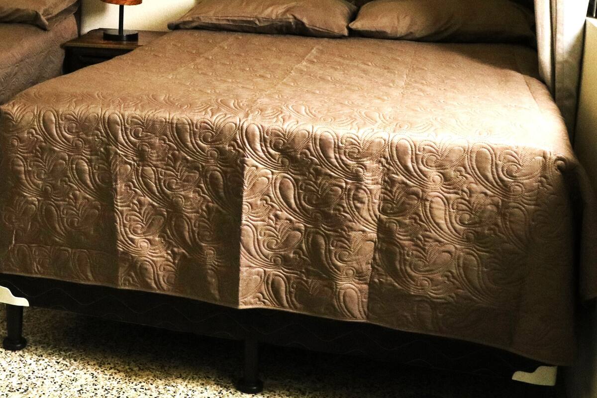 Ein Schlafzimmer mit einem Bett, einem Nachttisch, einer Lampe und einem gerahmten Bild an der Wand.