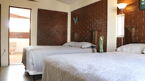 A room with two beds, a brick wall, a butterfly decoration, and a door leading to an outdoor area. - Hostal los Volcanes ciudad de Guatemala (Guatemala City)