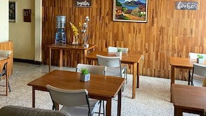 A cozy dining area with wooden walls and tables, a water dispenser, and decorative items. - Hostal los Volcanes ciudad de Guatemala (Guatemala City)