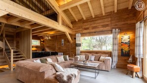 A spacious living area with a large sectional sofa, a coffee table, and a staircase leading to an upper level.