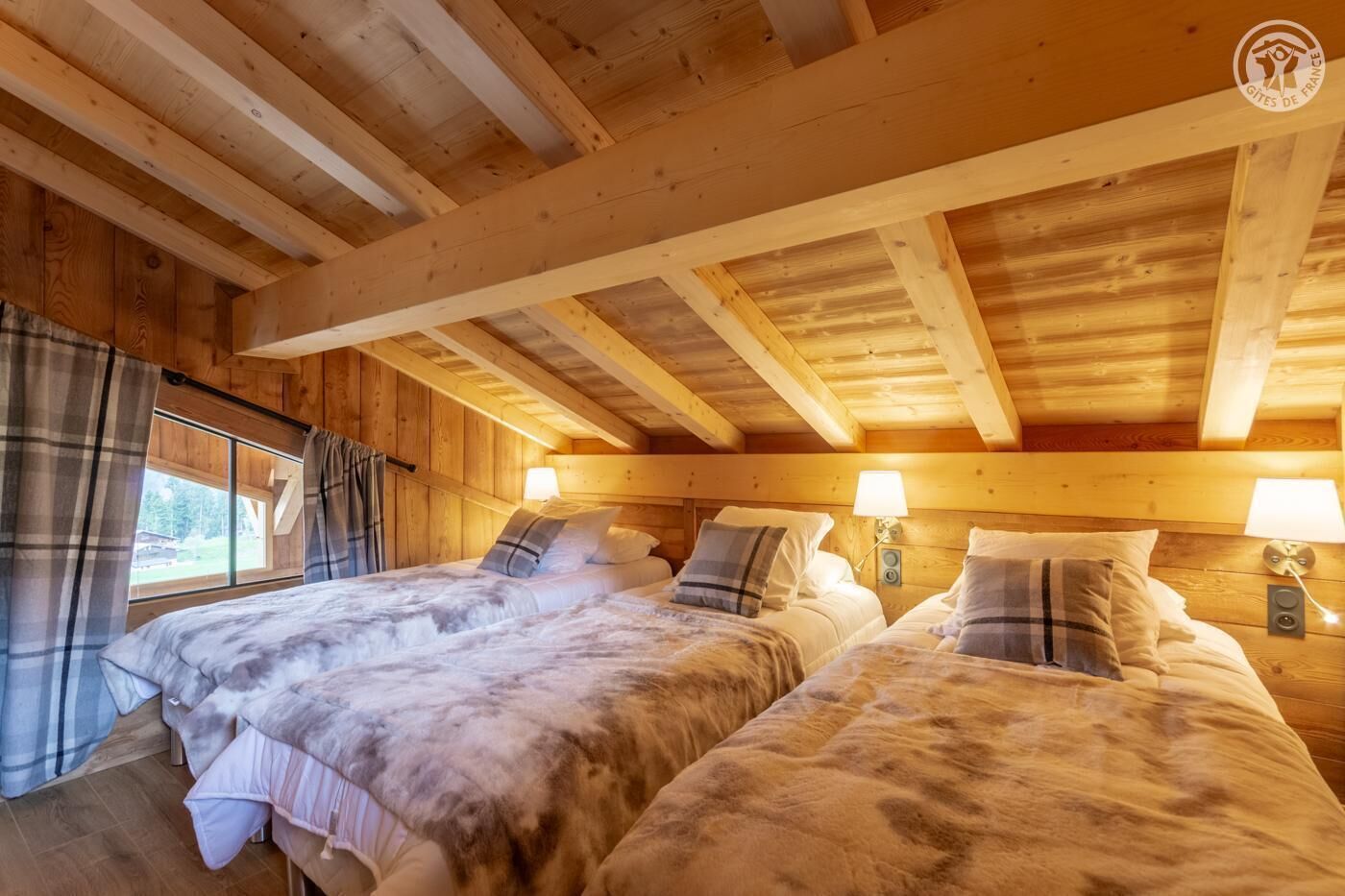 A cozy wooden cabin room with two beds, each with a pillow and a bedside lamp.