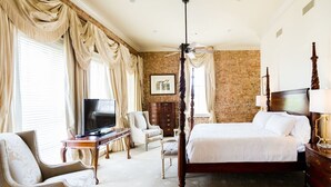 A spacious bedroom with a large bed, a television, a desk, and a chair. - The River Walk Inn  - Room 806 (Natchez)