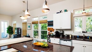 Una cocina moderna con encimeras de granito, armarios blancos y una isla grande.