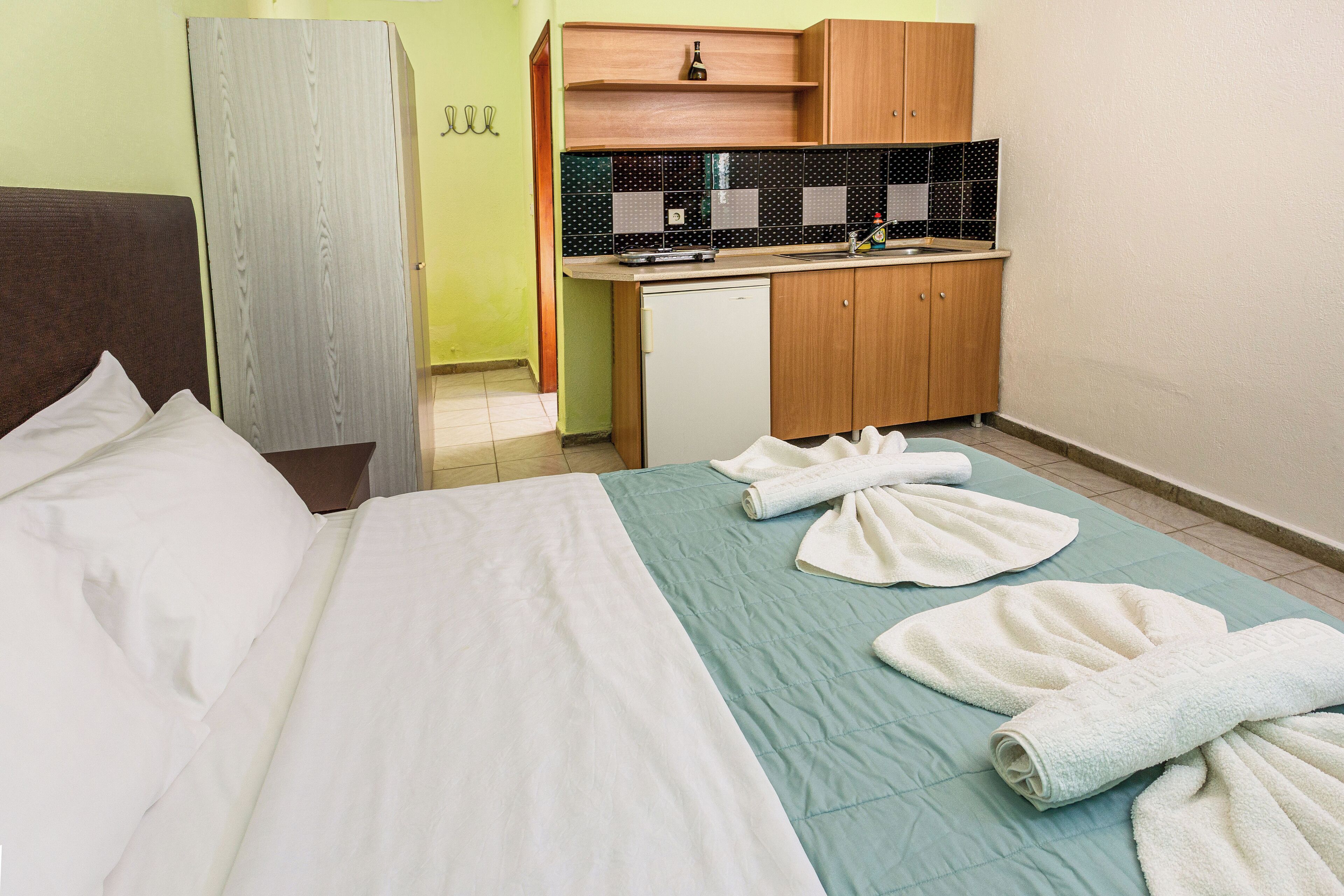 Una habitación de hotel con cama, kitchenette pequeño y baño.