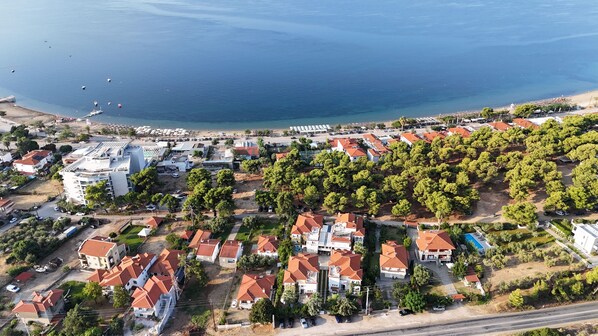 An aerial view of a coastal residential area with houses, a beach, and boats. - Hotel Melissa Gold Coast (Polygyros)