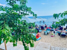 En la playa, arena blanca, sillas reclinables de playa, sombrillas