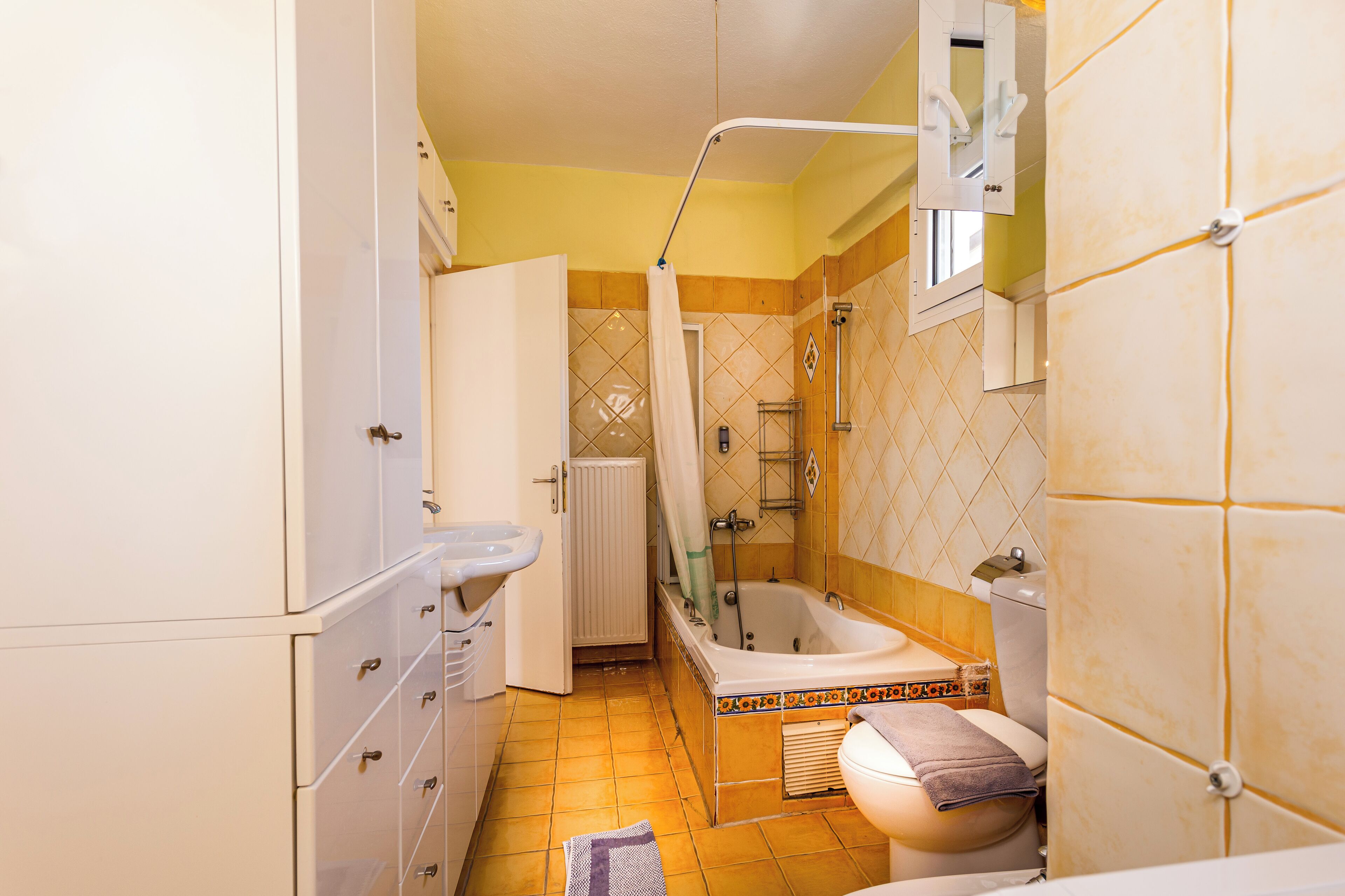 Een kleine badkamer met bad, toilet en wastafel.