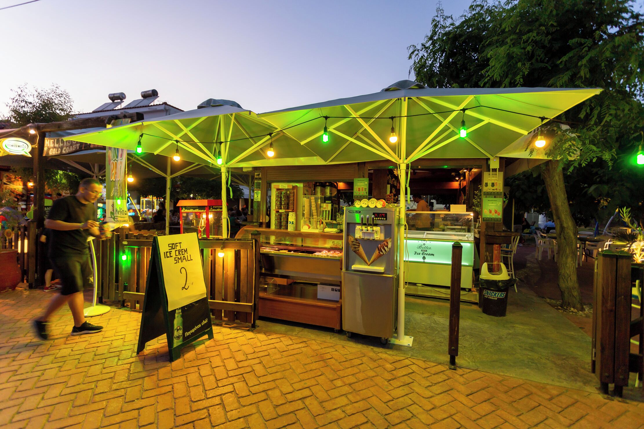 A food cart with a sign for soft ice cream, a cash register, and a menu board.