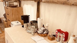 A rustic tent interior with a table set for dining, including plates, cutlery, and a first aid kit.
