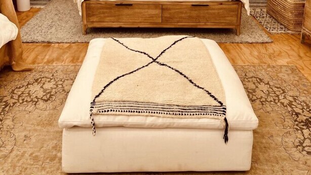 A cozy, tent-style bedroom with a wooden bed, a hanging woven light fixture, and a rustic decor theme.