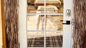 A door with a view into a room featuring a bed, a small table, and a patterned rug.