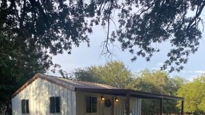 A small, single-story cabin with a covered porch and a patio area.