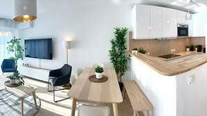 A modern apartment with a bunk bed, living room, dining area, kitchen, and a small balcony.
