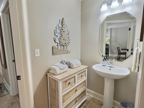 A bathroom with a vanity, sink, mirror, and decorative tree wall art. - Legacy at the Summit - 2 Balconies, Mountain Views, Walk Downtown (Gatlinburg)