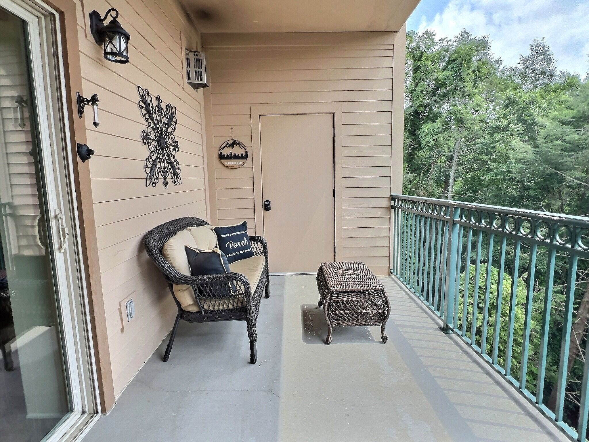 A balcony with a wicker chair and ottoman, a door, and decorative wall elements.