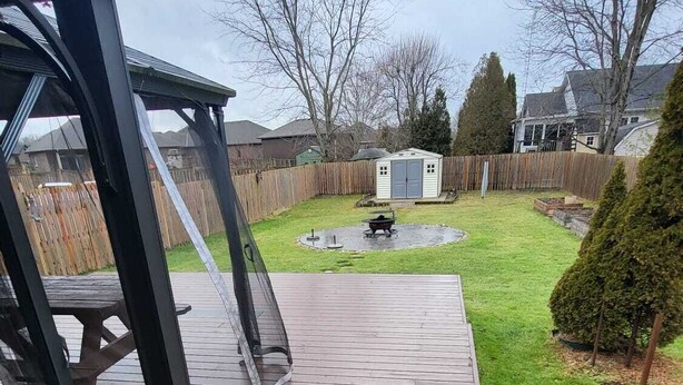 A wooden deck with a picnic table and a small shed in the background. - Spacious and Modern Home, 10 mins to Restaurants, Shops and Parks. (Welland)