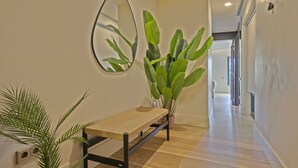 A hallway with a bench, a mirror, and a large plant. - Paseo de Gracia1 (Barcelona)