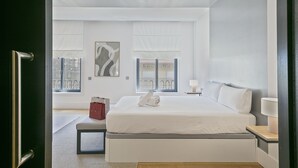 A modern hotel room with a large bed, a bedside table with a lamp, and a view of the balcony through the window. - Paseo de Gracia1 (Barcelona)