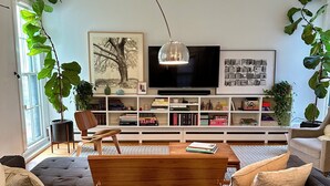 A modern living room with a wooden coffee table, a record player, a TV, and bookshelves. - Cozy & Modern Victorian in Historic Allentown, Buffalo (Buffalo)