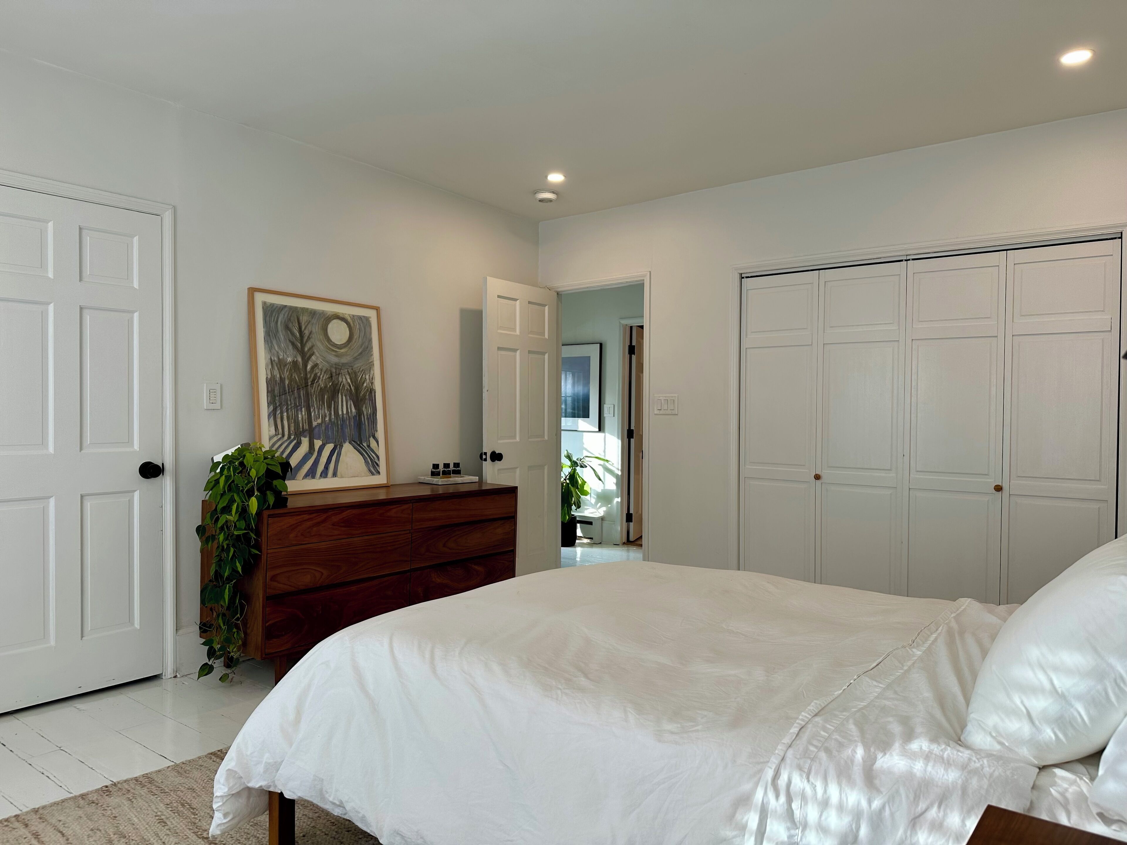 A bedroom with a large bed, a dresser, a mirror, and a closet.