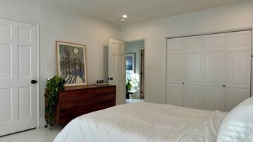 A bedroom with a large bed, a dresser, a mirror, and a closet.