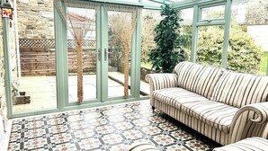 A conservatory with a patterned floor, a striped sofa, and a view of the garden. - Cosy Self Catering Family Home in a Quaint Village Setting (Wetherby)