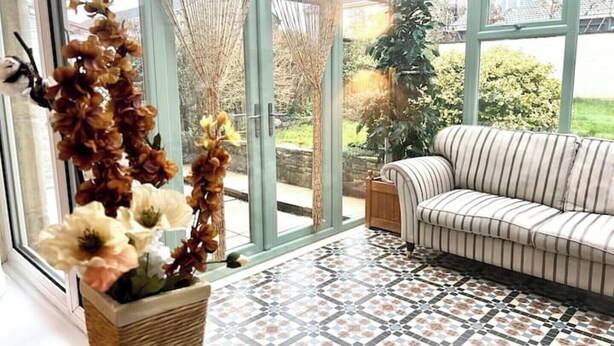 A conservatory with a patterned floor, a striped sofa, and decorative plants. - Cosy Self Catering Family Home in a Quaint Village Setting (Wetherby)