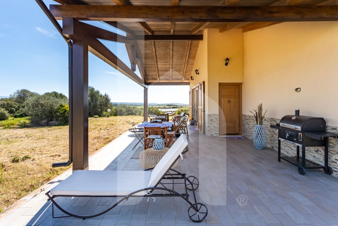Eine Terrasse im Freien mit Tisch, Stühlen, einem Grill und Blick auf die Landschaft.