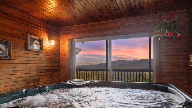Eine Holzhütte mit Whirlpool und Bergblick.