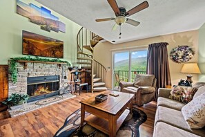 A living room with a fireplace, a staircase, and a view of the outdoors.