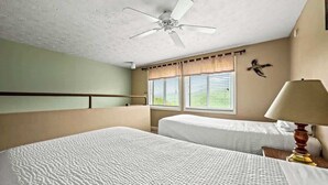 A hotel room with two beds, a ceiling fan, a window with blinds, and a wall-mounted lamp. - Sleeps 8 Pool Playground Mountain Views Hot Tub (Gatlinburg)
