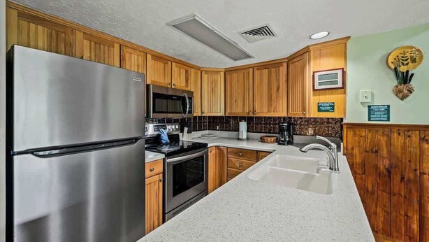 A modern kitchen with wooden cabinets, stainless steel appliances, and a white countertop. - Sleeps 8 Pool Playground Mountain Views Hot Tub (Gatlinburg)