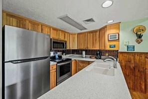 Una cocina moderna con armarios de madera, electrodomésticos de acero inoxidable y encimera blanca.