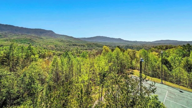 A tennis court surrounded by dense forest and hills. - Full Kitchen Hot Tub Indoor Pool Sleeps 6 (Gatlinburg)