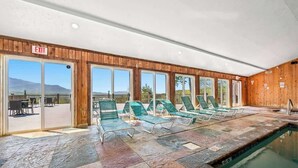 An indoor swimming pool with green lounge chairs and an exit sign. - Full Kitchen Hot Tub Indoor Pool Sleeps 6 (Gatlinburg)