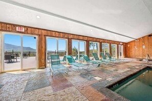 An indoor swimming pool with green lounge chairs and an exit sign. - Full Kitchen Hot Tub Indoor Pool Sleeps 6 (Gatlinburg)