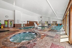 Ampla área interna com piscina, hidromassagem, espreguiçadeiras e uma parede de madeira.