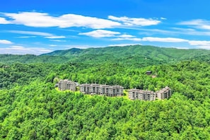 A multi-story hotel with a modern design, surrounded by lush greenery and hills. - Gatlinburg Mountain Condo w/ Pool, Hot Tub, Views (Gatlinburg)