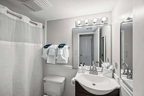 A modern bathroom with a shower, toilet, sink, and vanity mirror. - Gatlinburg Mountain Condo w/ Pool, Hot Tub, Views (Gatlinburg)