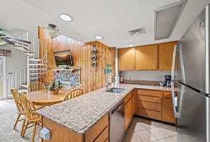 Una cocina con armarios de madera, encimeras de granito, refrigerador de acero inoxidable y lavavajillas integrado.