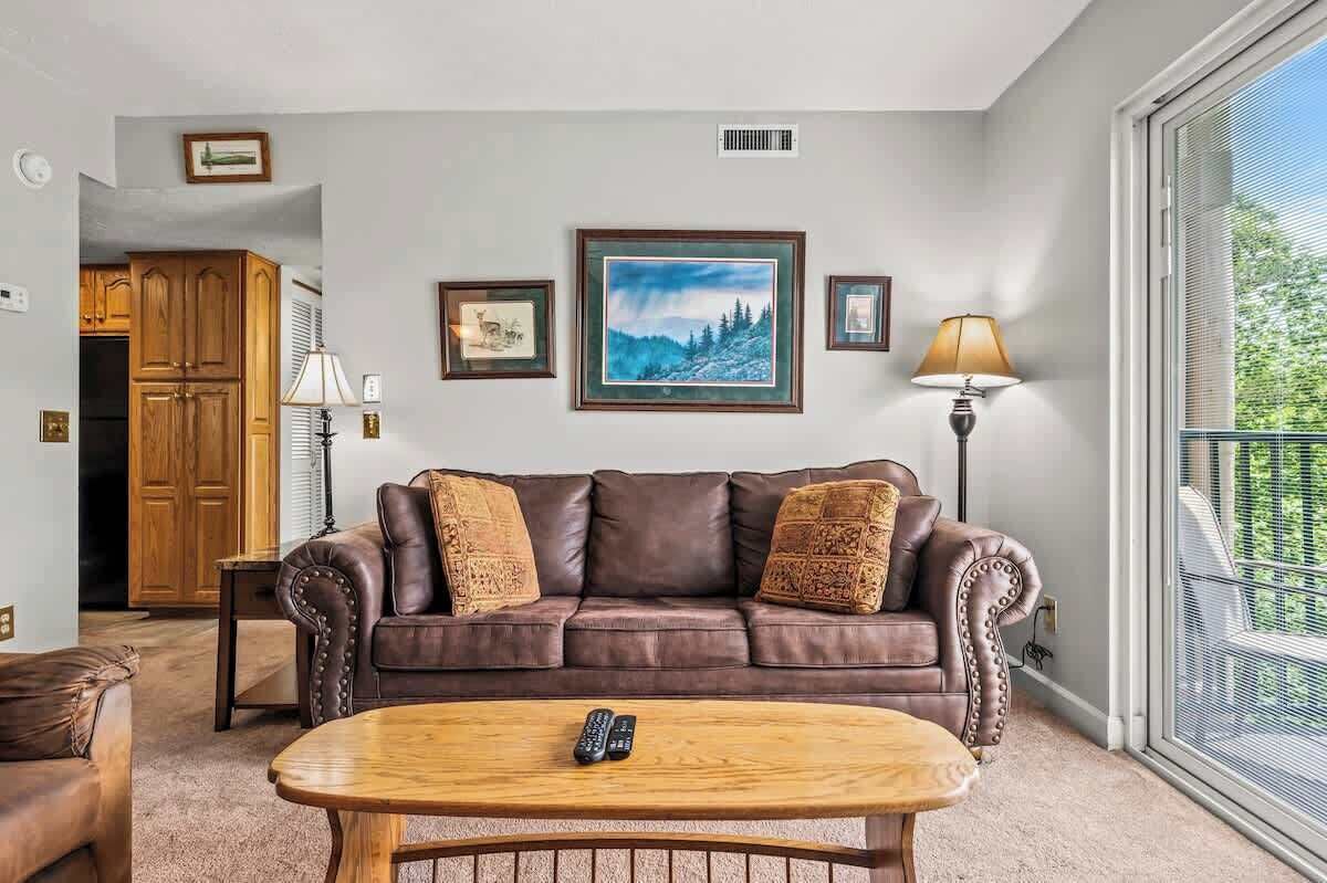 A living room with a brown leather sofa, a wooden coffee table, and a framed painting on the wall.